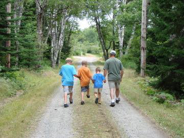 CEO Jim McKenna walking down a Maine dirt road with his three young sons