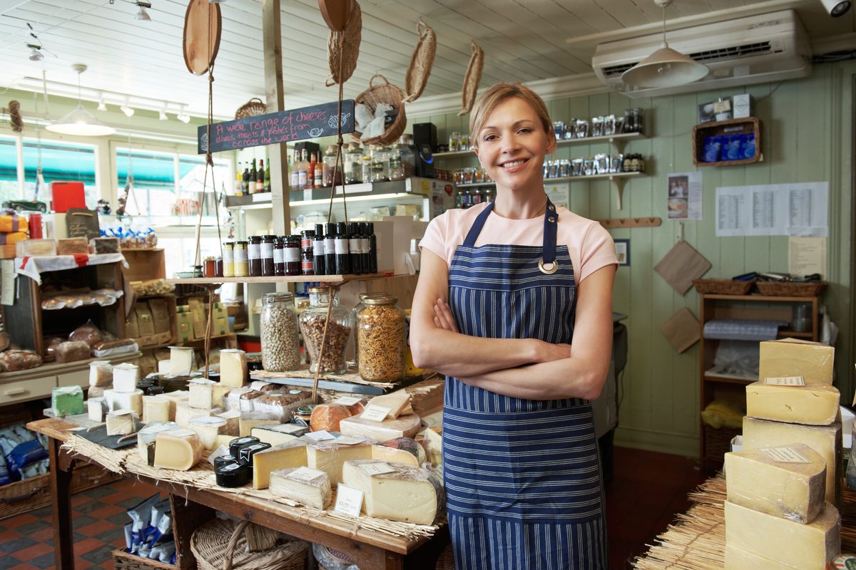 A shop owner in an apron standing in her store